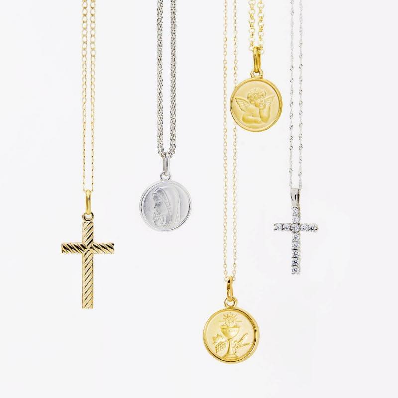 cruces y medallas de comunion con cadenas sobre un fondo de color blanco. Las cruces son de oro 18k y están disponibles para comprar en Joyeria Marga Mira